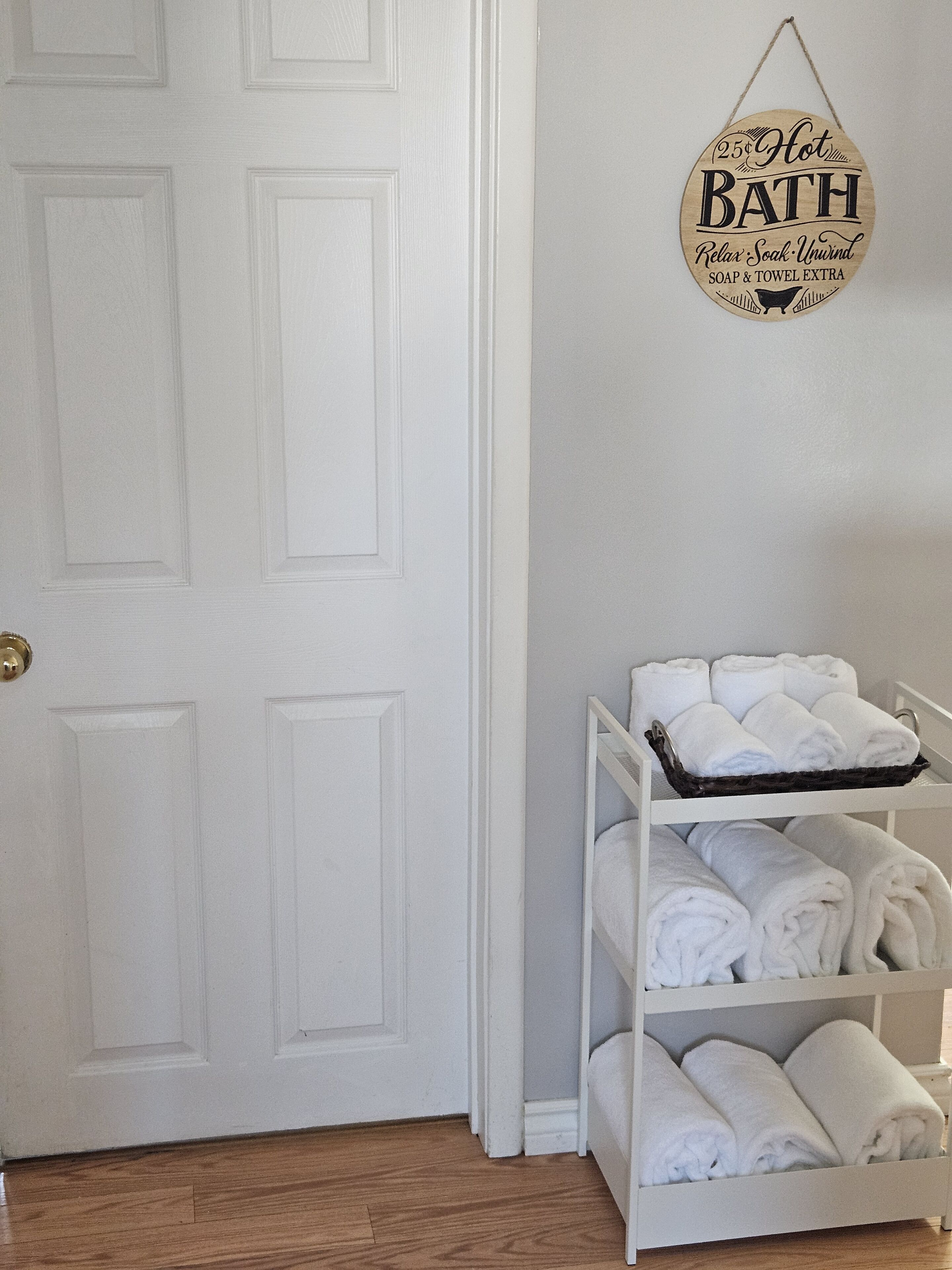 A white door with a sign above it that reads "25¢ Hot Bath Relax Soak Unwind Soap & Towel Extra".