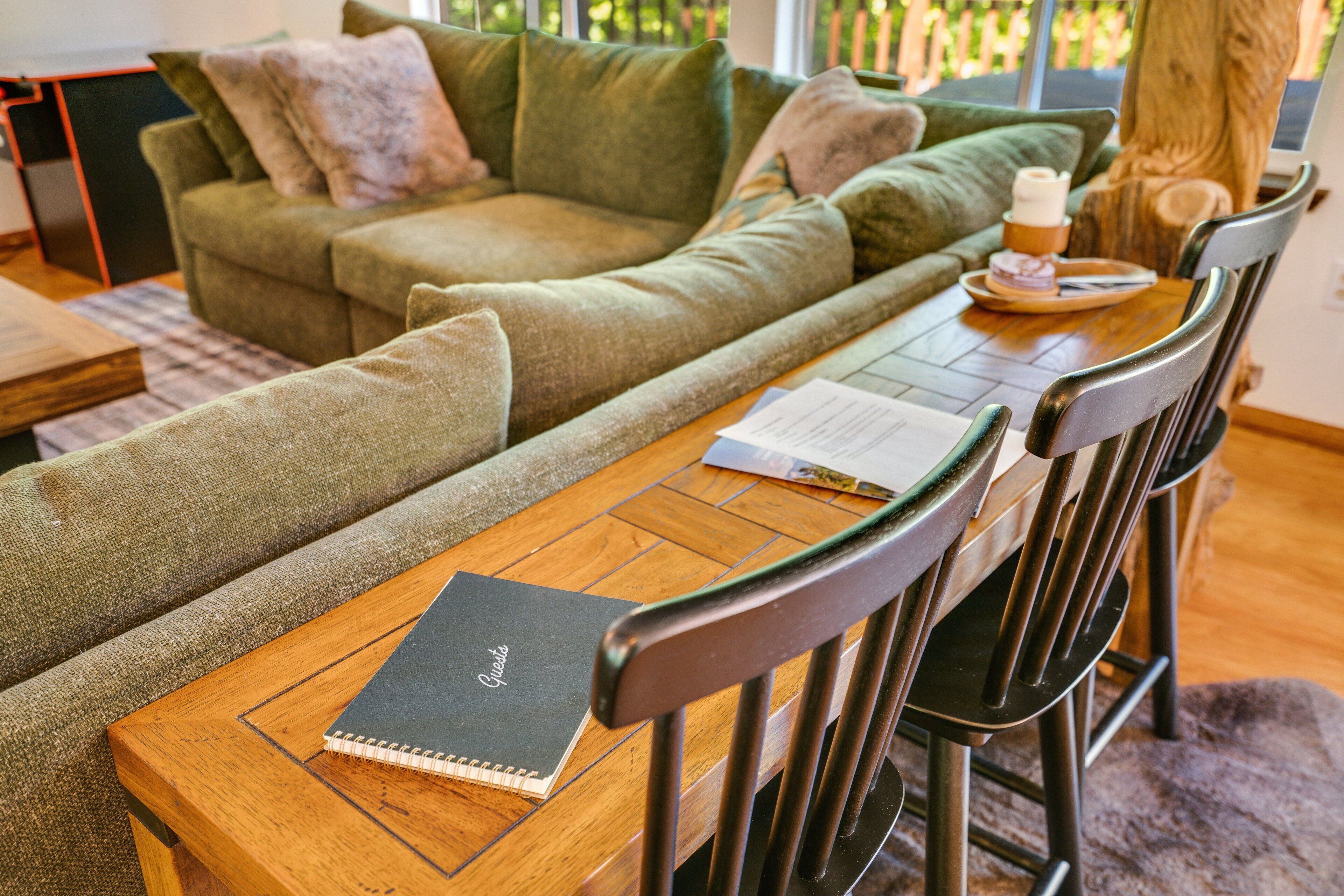 A cozy living area with a green sofa, wooden coffee table, and a notebook on a chair.