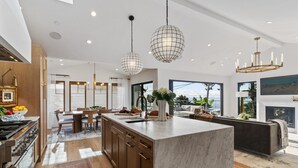 Une cuisine moderne avec un îlot en marbre, des armoires en bois et des luminaires suspendus.