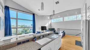 Une cuisine moderne dotée d’un grand îlot central, de meubles blancs et offrant une vue sur la ville.