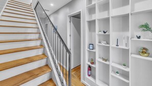Un escalier avec des marches en bois et une rampe en métal, menant à une porte blanche.