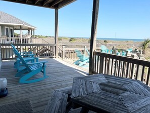 A wooden deck with blue Adirondack chairs and a picnic table overlooking the beach. - Fins / 1295 Ocean Blvd West 10 Bedroom Home (Supply)