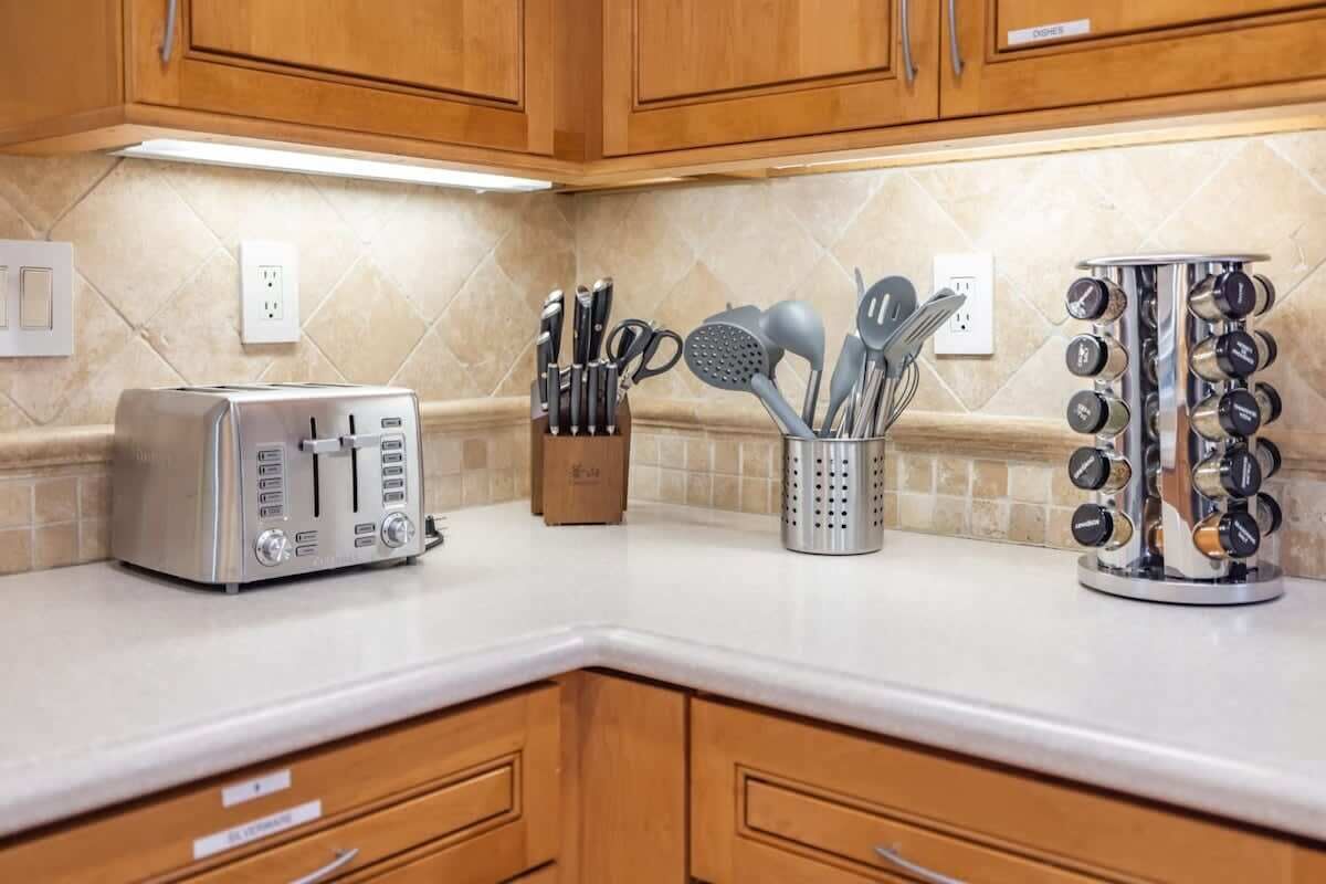 Una cocina con armarios de madera, un tostador, un bloque de cuchillos y un especiero.