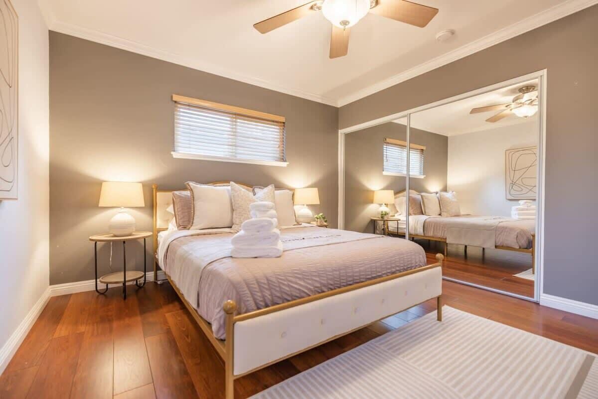 Una camera da letto con un letto, comodini, una ventola a soffitto e un grande specchio.