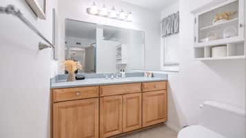 Une salle de bain avec un meuble-lavabo en bois, un grand miroir et des toilettes blanches.