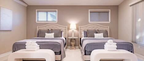 A bedroom with two beds, a bedside table, and a lamp.