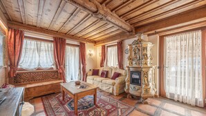 A traditional room with a wooden ceiling, a sofa, a patterned rug, and a decorative cabinet. - Casa Col, near the ski slopes with view of the Dolomites (Cortina d´Ampezzo)