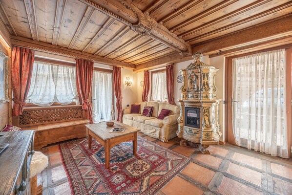 Une pièce au décor traditionnel, avec un plafond en bois, un canapé, un tapis à motifs et un meuble décoratif.