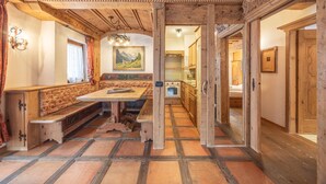 A wooden interior with a bench, table, and kitchen area. - Casa Col, near the ski slopes with view of the Dolomites (Cortina d´Ampezzo)