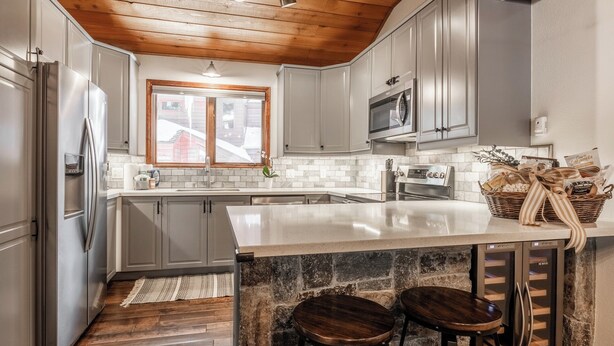 A kitchen with a central island, wooden ceiling, and a stone accent wall. - Winterset Luxe 2 bedroom+Loft in the heart of Mammoth Lakes (Mammoth Lakes)