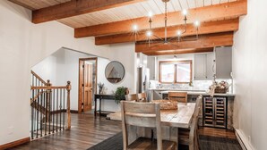 A spacious kitchen with wooden beams, a dining area with a table and chairs, and a staircase leading to another level. - Winterset Luxe 2 bedroom+Loft in the heart of Mammoth Lakes (Mammoth Lakes)