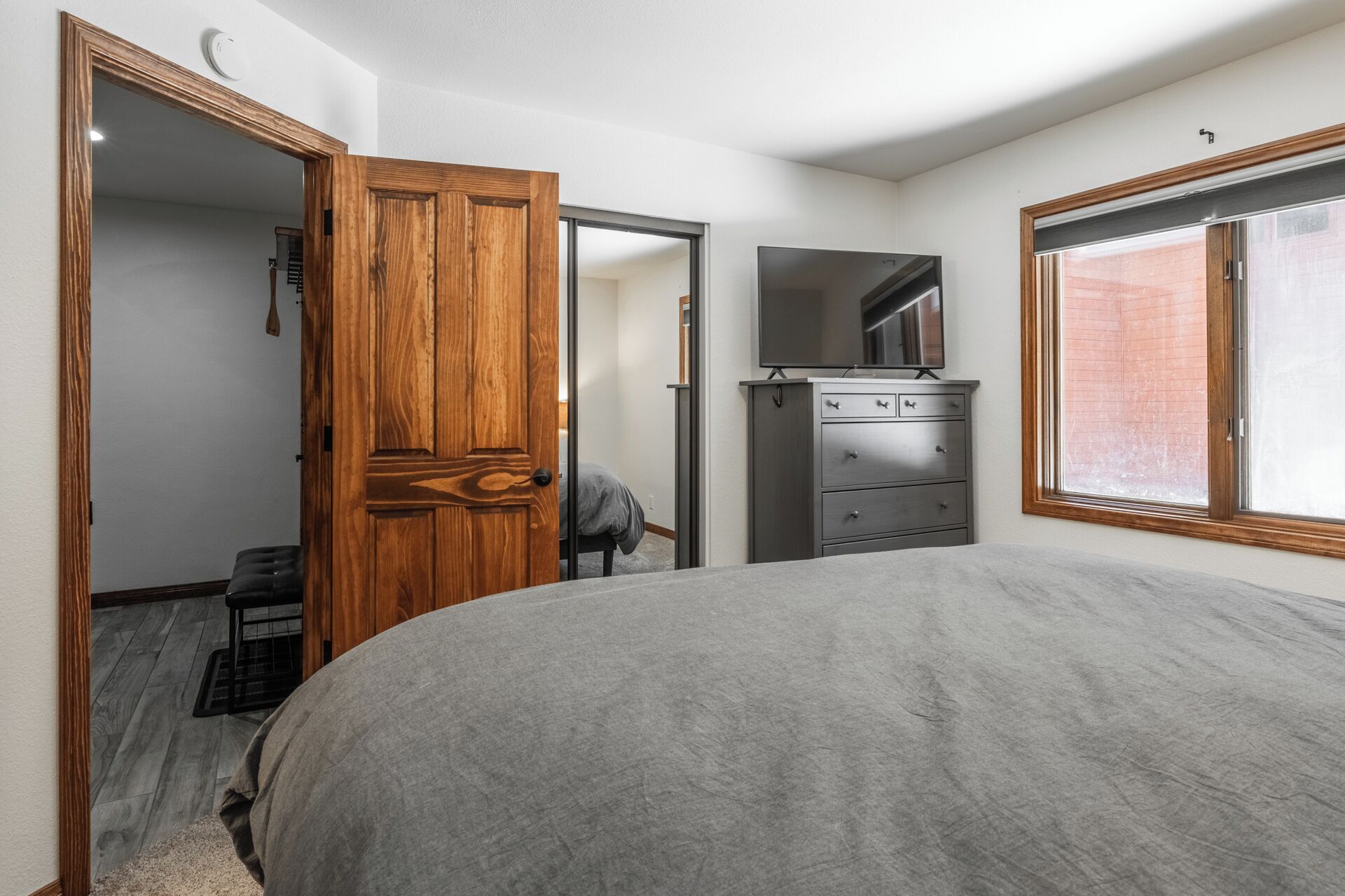 Un dormitorio con una cama grande, un aparador, un espejo y una ventana.