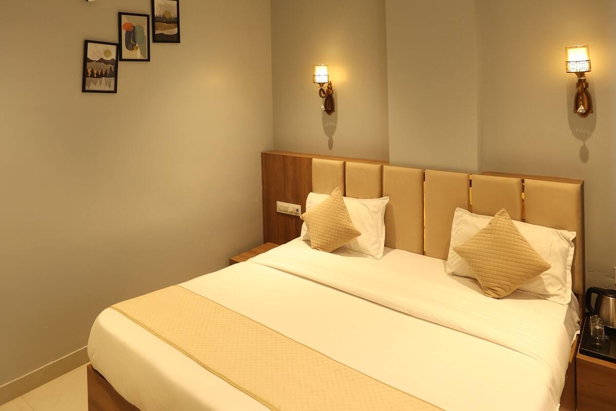 Quarto com cama grande, ventilador de teto, luminárias fixadas na parede e quadros decorativos.