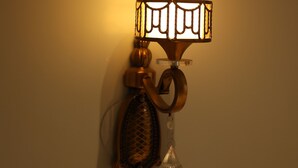 A wall-mounted lamp with a clear glass shade and a decorative metal frame. - Hotel Trinay (Jaipur)