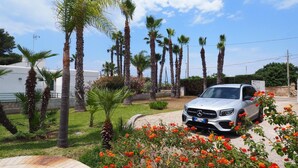 A white Mercedes-Benz SUV parked in a well-maintained garden with palm trees and flowering plants. - Villa Malaspina - Hot Tub, 3 Bedrooms, Sleeps 6 (Alliste)