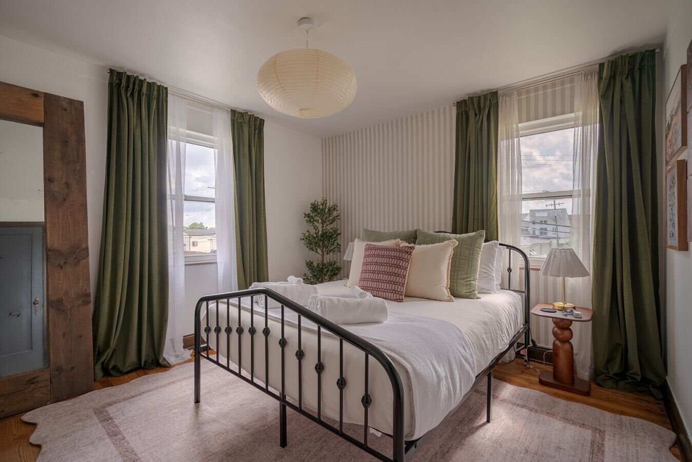 Une chambre à coucher avec un lit, une lampe de chevet, une fenêtre et des rideaux.