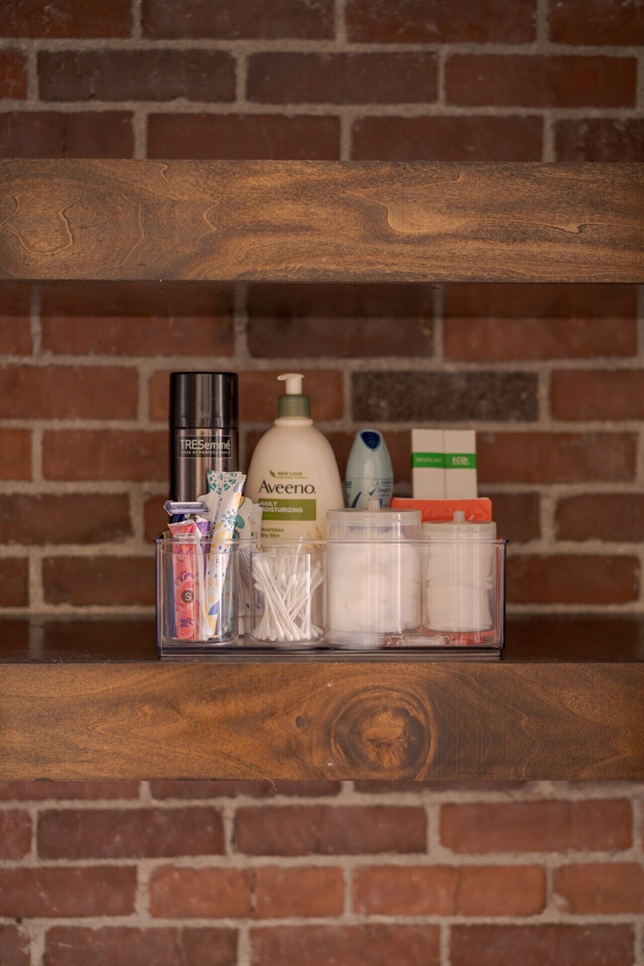 Une étagère contenant des articles de toilette, notamment une lotion Aveeno, un flacon noir et divers autres produits.