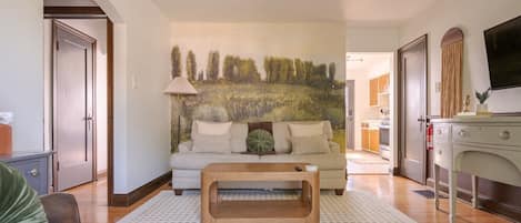 A living room with a sofa, coffee table, and a painting on the wall.
