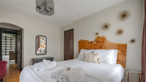 A bedroom with a wooden headboard, a bed with white linens, a nightstand, a mirror, and decorative wall art. - Minutes from OSU Stadium | Walkable | Quiet Area (Columbus)