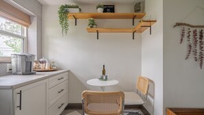A compact kitchen with a coffee maker, two chairs, a small table, and wooden shelves with plants. - Minutes from OSU Stadium | Walkable | Quiet Area (Columbus)