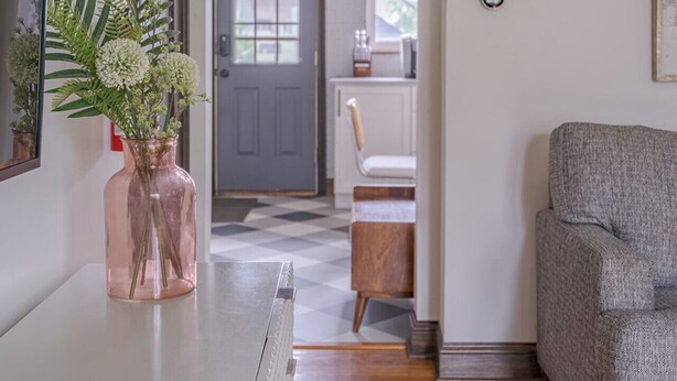A hallway with a dining area, a gray sofa, and a door with a window. - Minutes from OSU Stadium | Walkable | Quiet Area (Columbus)