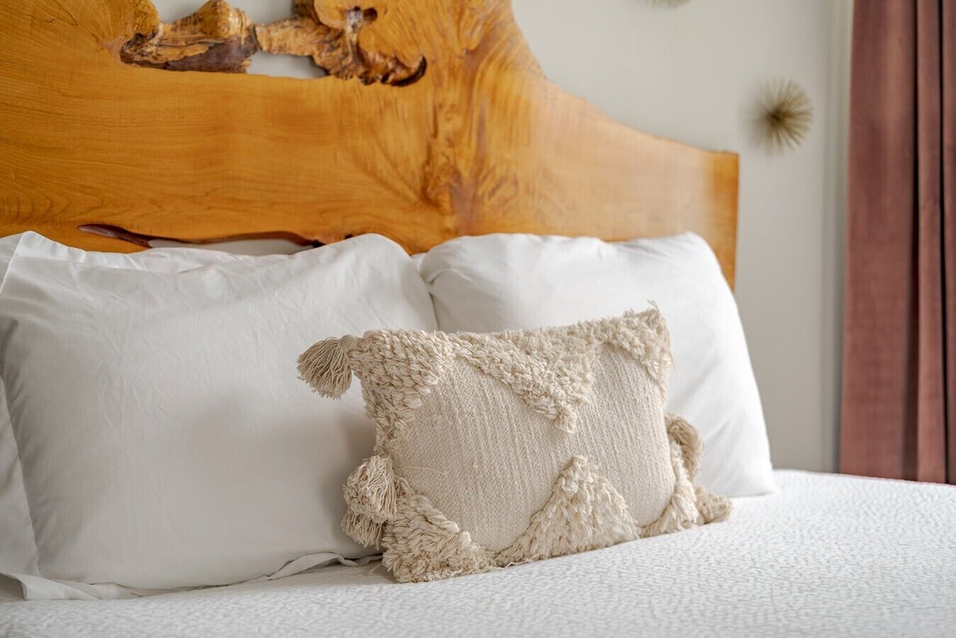 Een bed met witte beddengoed, een houten hoofdbord en twee kussens.