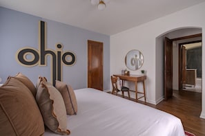 Une chambre à coucher avec un lit, un bureau, une chaise, un miroir et une porte.