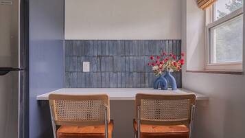 A kitchen with two bar stools, a window with a view, and a backsplash with a grid pattern.