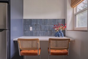 A kitchen with two bar stools, a window with a view, and a backsplash with a grid pattern. - Free Laundry | Walkable to OSU | Free Parking (Columbus)