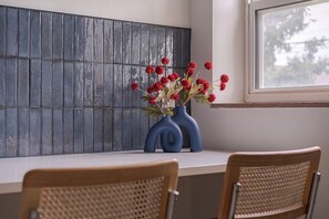 Une pièce avec un mur carrelé, une fenêtre et une table entourée de chaises.