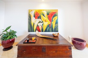 A wooden table with a painting of flowers, a candle, and a bowl.