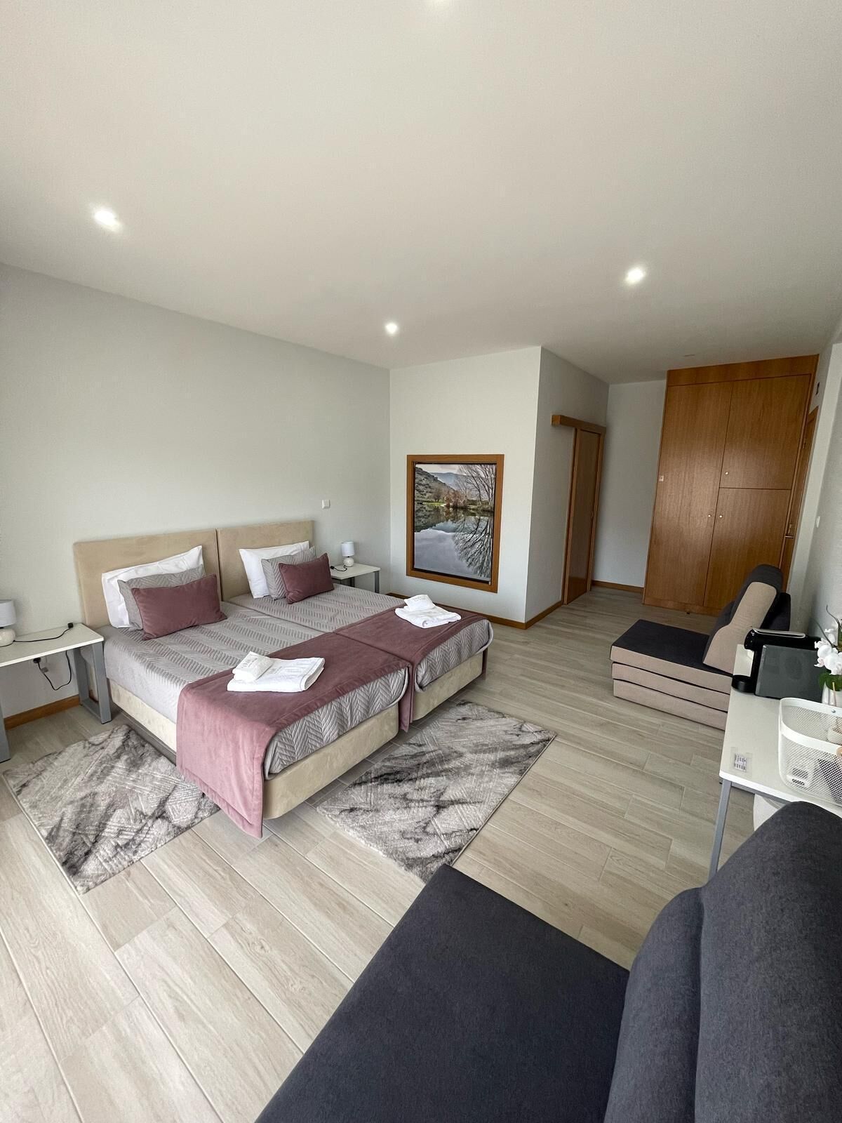 A modern bedroom with a bed, bedside tables, a desk, a chair, and a wardrobe.
