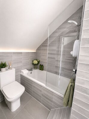 A modern bathroom with a shower, toilet, and sink.