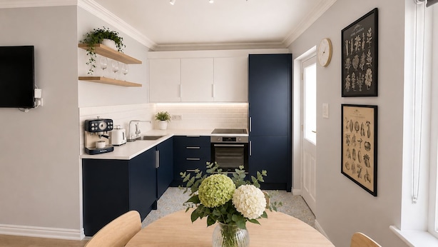 A modern kitchen with white and navy blue cabinets, a coffee machine, and a dining table with a vase of flowers. - Super City Centre Location - Sleeps 5 (Galway)