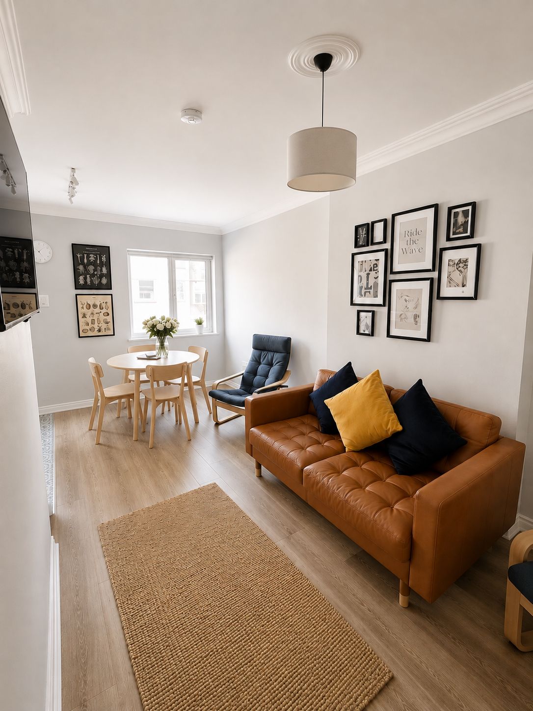 A modern living room with a brown leather sofa, a dining table with chairs, and a large window.