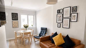 A modern living room with a brown leather sofa, a dining table with chairs, and a large window. - Super City Centre Location - Sleeps 5 (Galway)