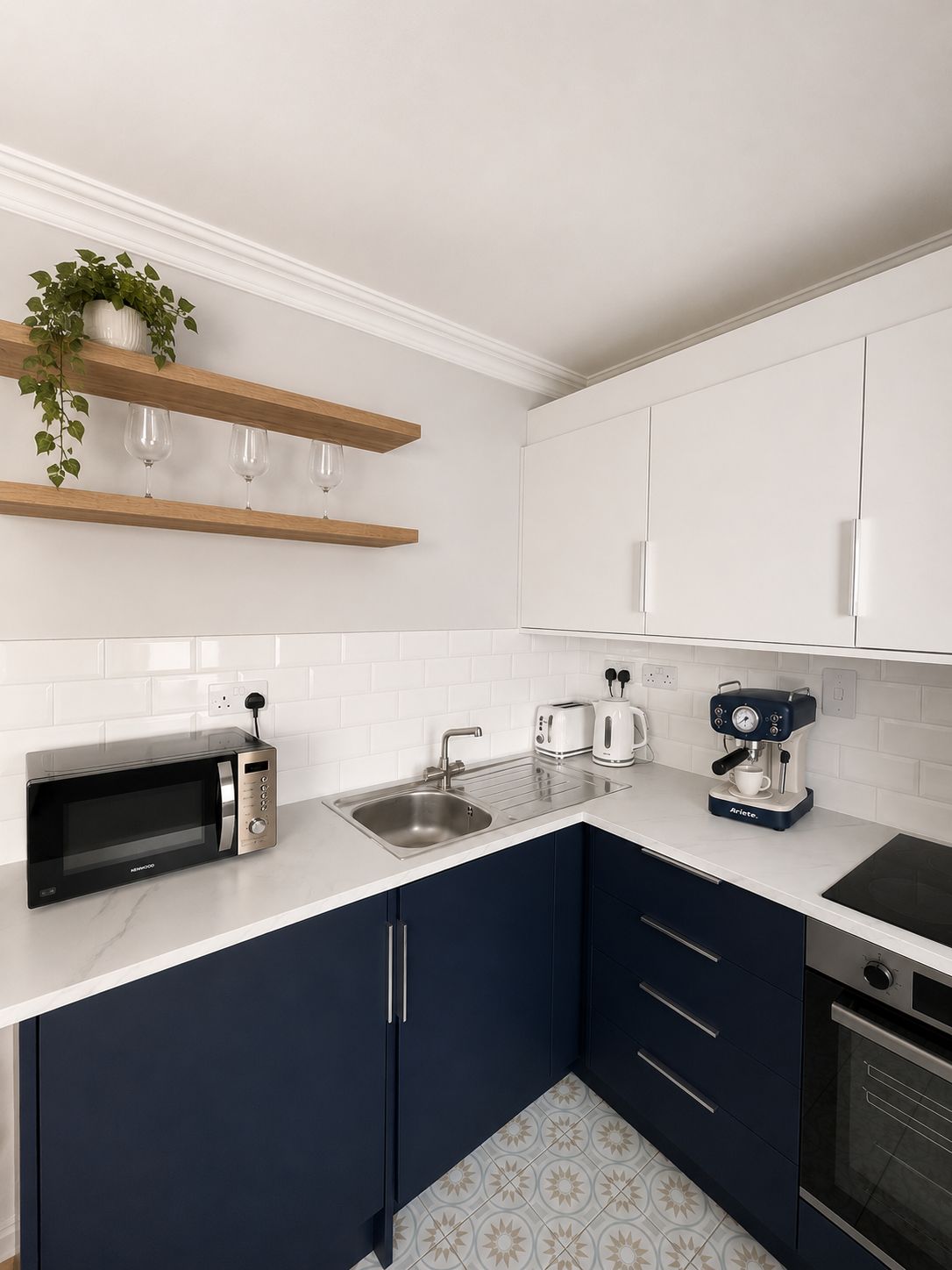 A modern kitchen with white cabinets, a black microwave, a coffee maker, and a sink.