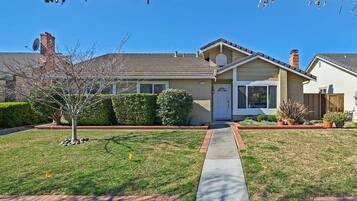 Stunning single-story home with a gabled roof and chimney, set amidst a beautifully maintained front yard.