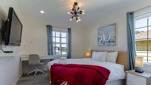 A hotel room with a bed, desk, chair, and a painting on the wall. - @ Marbella Lane - Convenient Home in Sunnyvale (Sunnyvale)