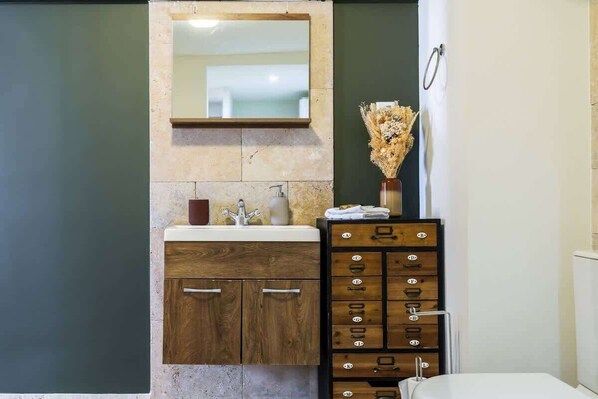 Un baño con lavabo, espejo, mueble de madera y un perchero para toallas.