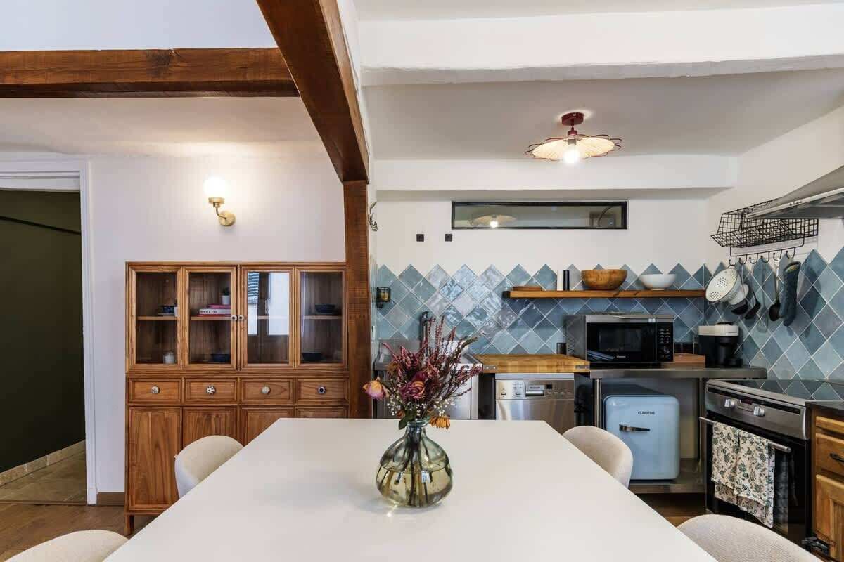 A modern kitchen with a dining area, wooden cabinets, a microwave, and a refrigerator.