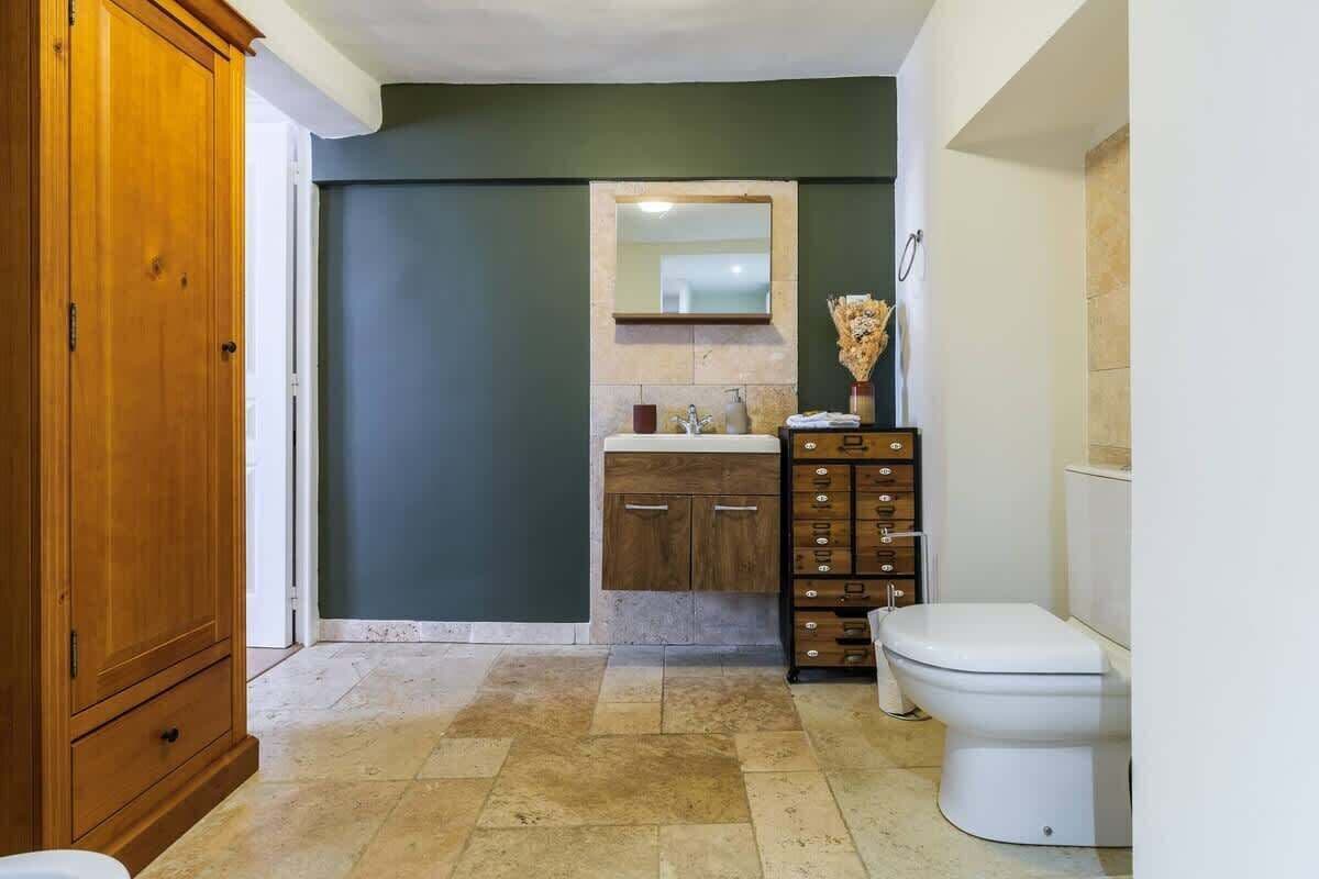Un baño con un mueble de madera, un lavabo con espejo y un inodoro.