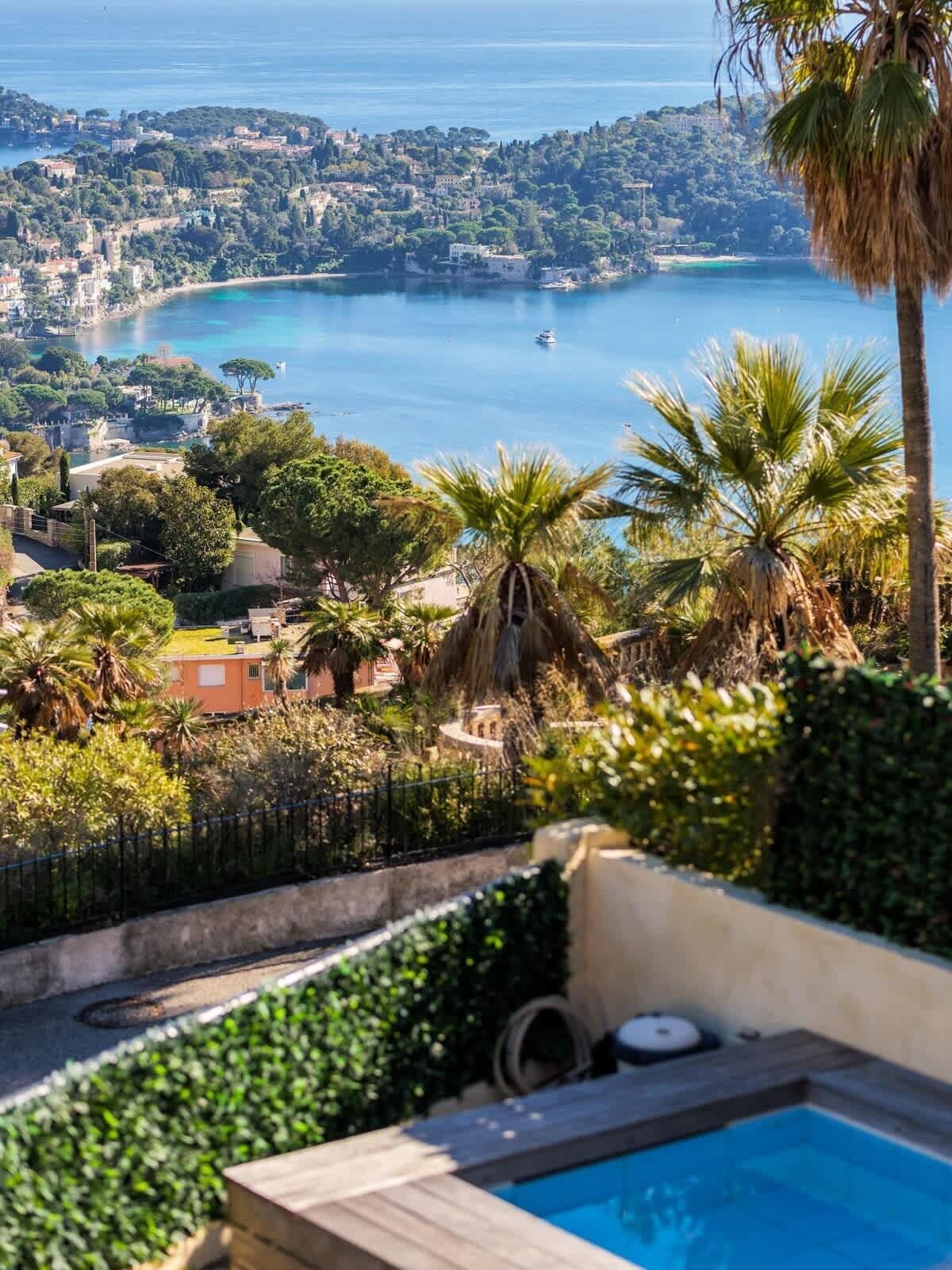 A pool with a view of the sea and a hillside town.