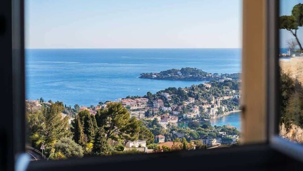 Un pueblo costero con vista al mar, edificios y zonas verdes.