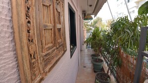 A narrow corridor with ornate wooden doors and potted plants. - Bibelot Acropolis (Athens)