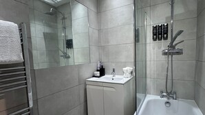 Un bany modern amb dutxa de vidre, banyera independent i un lavabo.
