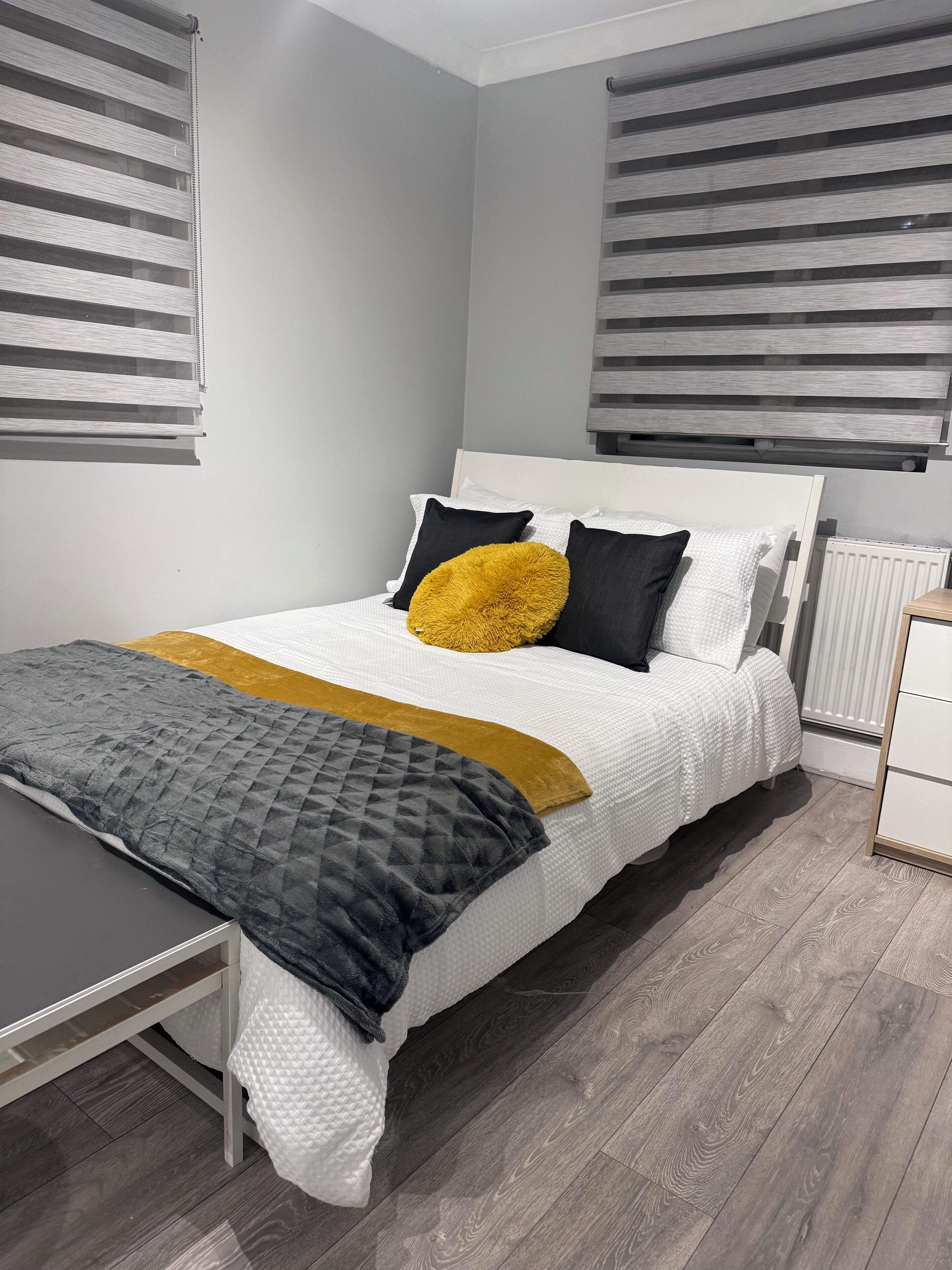 Een moderne slaapkamer met een bed, nachtkastjes en een radiator.