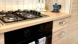 Een moderne keuken met een gasfornuis, oven en houten kastjes.