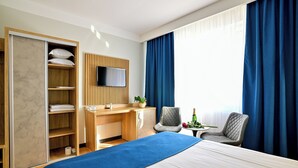 A hotel room with a bed, a desk, a TV, and a wardrobe.