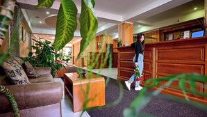 A hotel lobby with a reception desk, a sofa, and a coffee table. - Hotel Class Sibiu (Sibiu)